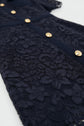 Close-up of a navy blue robe en dentelle featuring floral patterns and a row of gold buttons down the front. The intricate lace detail is prominent, giving this elegant robe longue with col chemise a refined and textured appearance.