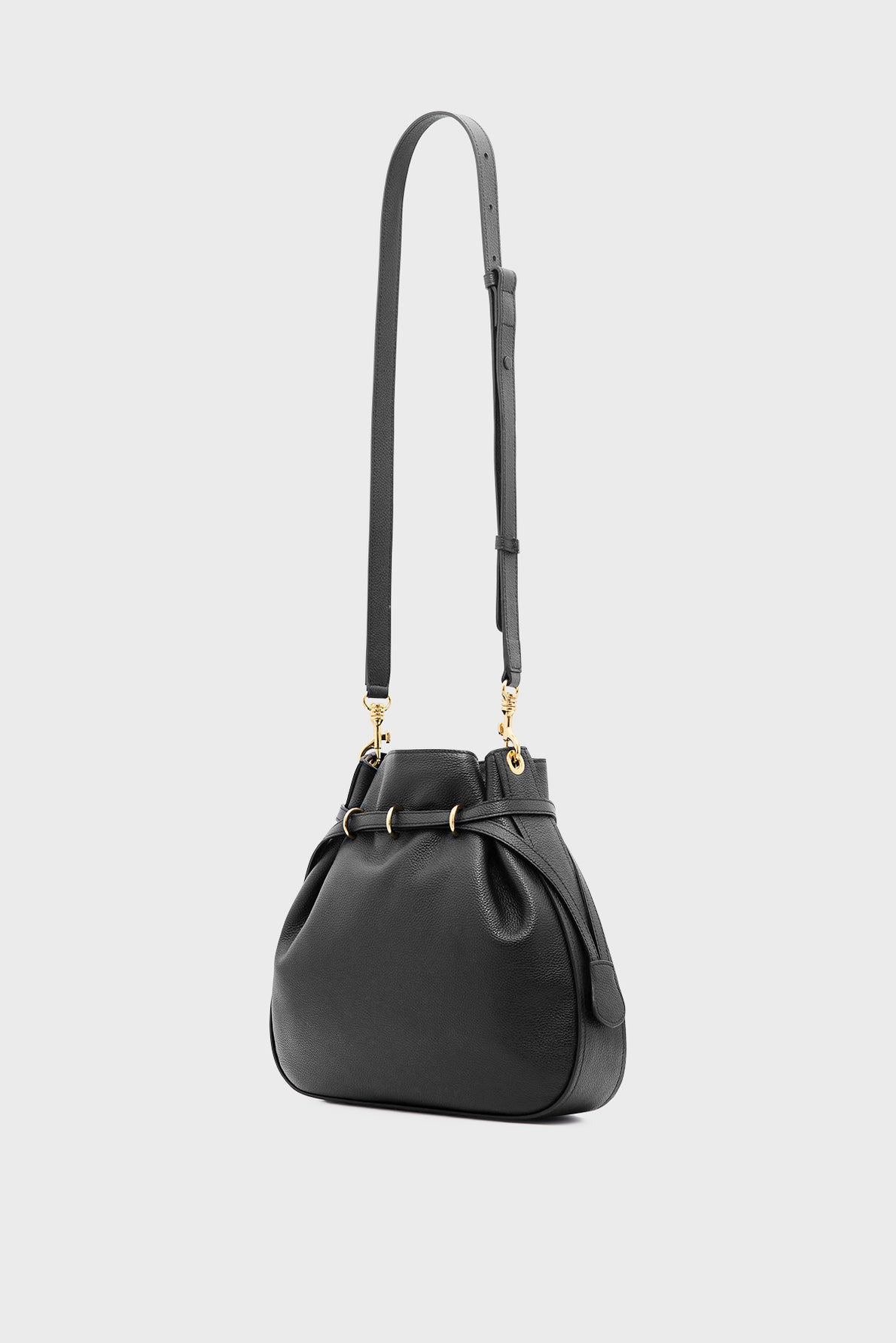 A black cuir grainé leather shoulder bag with gold hardware and an adjustable strap, set against a plain light grey background. The sac seau style features a soft, rounded shape with subtle pleating near the top, epitomizing une élégance sophistiquée.