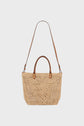 A beige woven straw tote bag, crafted with savoir-faire artisanal, features two short handles and a long adjustable brown leather shoulder strap, displayed against a plain white background—making it the perfect sac à main raphia for your collection.