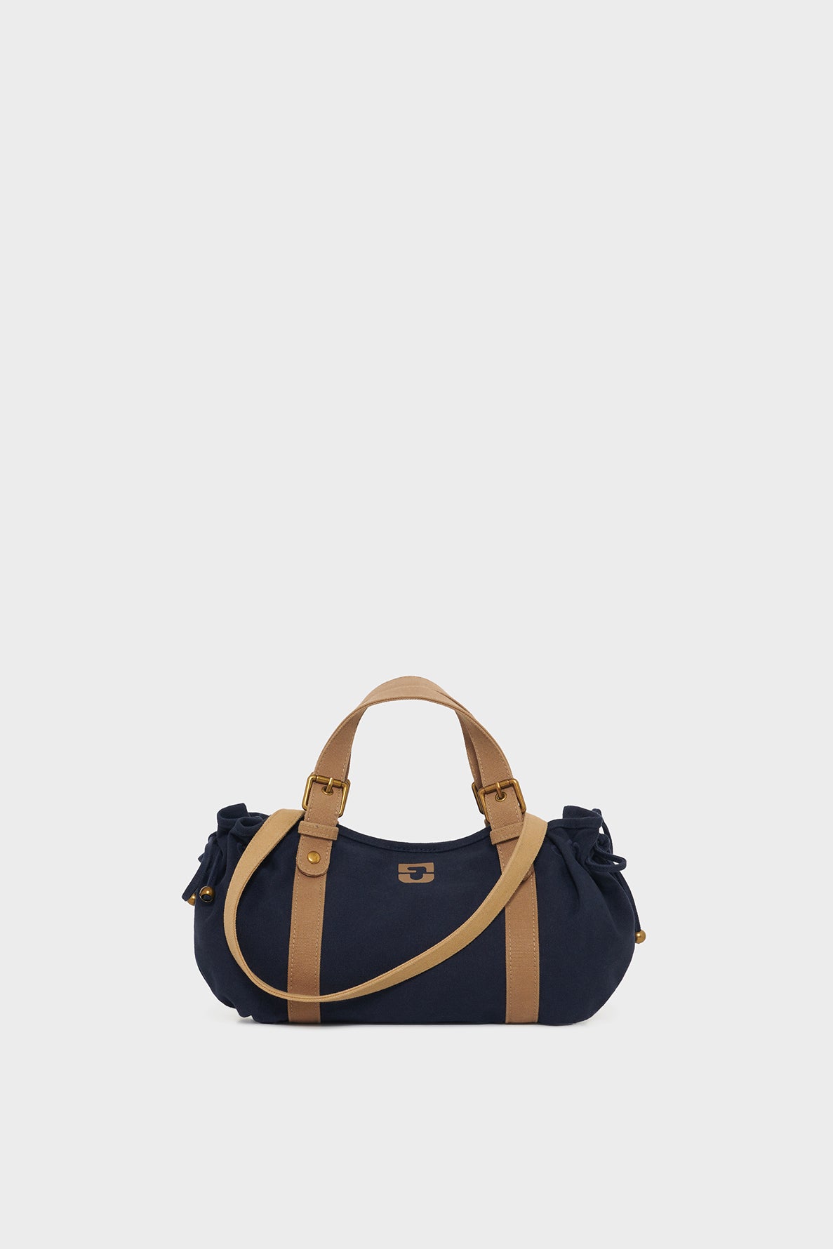 A navy blue GD Canvas duffel bag with tan handles and straps is centered on a plain light gray background. The sac à main features small metal accents and gathered sides.