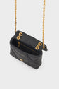 A small black quilted sac bandoulière cuir with a gold chain strap, gold hardware, a button closure, and an inner zip pocket, viewed from above on a white background.