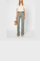 Person wearing a white lace top with manches courtes, floral print flared pants, tan wedge shoes, and a brown belt, holding a small tan handbag, standing against a plain white background.