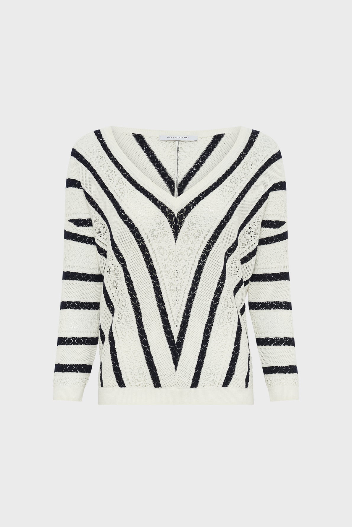 A white knit sweater with black V-shaped and horizontal stripes, featuring a wide neckline and three-quarter sleeves.