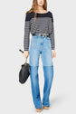 Woman wearing a black and white striped long-sleeve shirt, high-waisted blue jeans with a horizontal seam, tan platform shoes, and carrying a black handbag with a chain strap.