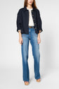A person wearing a veste oversize navy jacket, white textured top, blue high-waisted jeans, and beige platform sandals stands against a plain background.