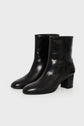 A pair of bottines cuir noir mi hautes avec un talon bloc, fabriquées en Italie, sont présentées côte à côte sur un fond blanc épuré.