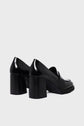 A pair of black patent leather mocassin femme loafers with chunky talon carré high block heels, viewed from the back and slightly to the side against a plain light gray background.