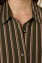 Close-up of a person wearing a chemise à rayures, featuring vertical pink and brown stripes on a green shirt. The chemise kaki has a collar and two visible buttons, with the top button left undone. The image is cropped at the neck and chest.