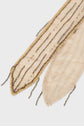 A close-up of a cream-colored fabric with gold foulard sequins and beaded strands sewn along the edge and parallel lines, creating an elegant, decorative pattern.