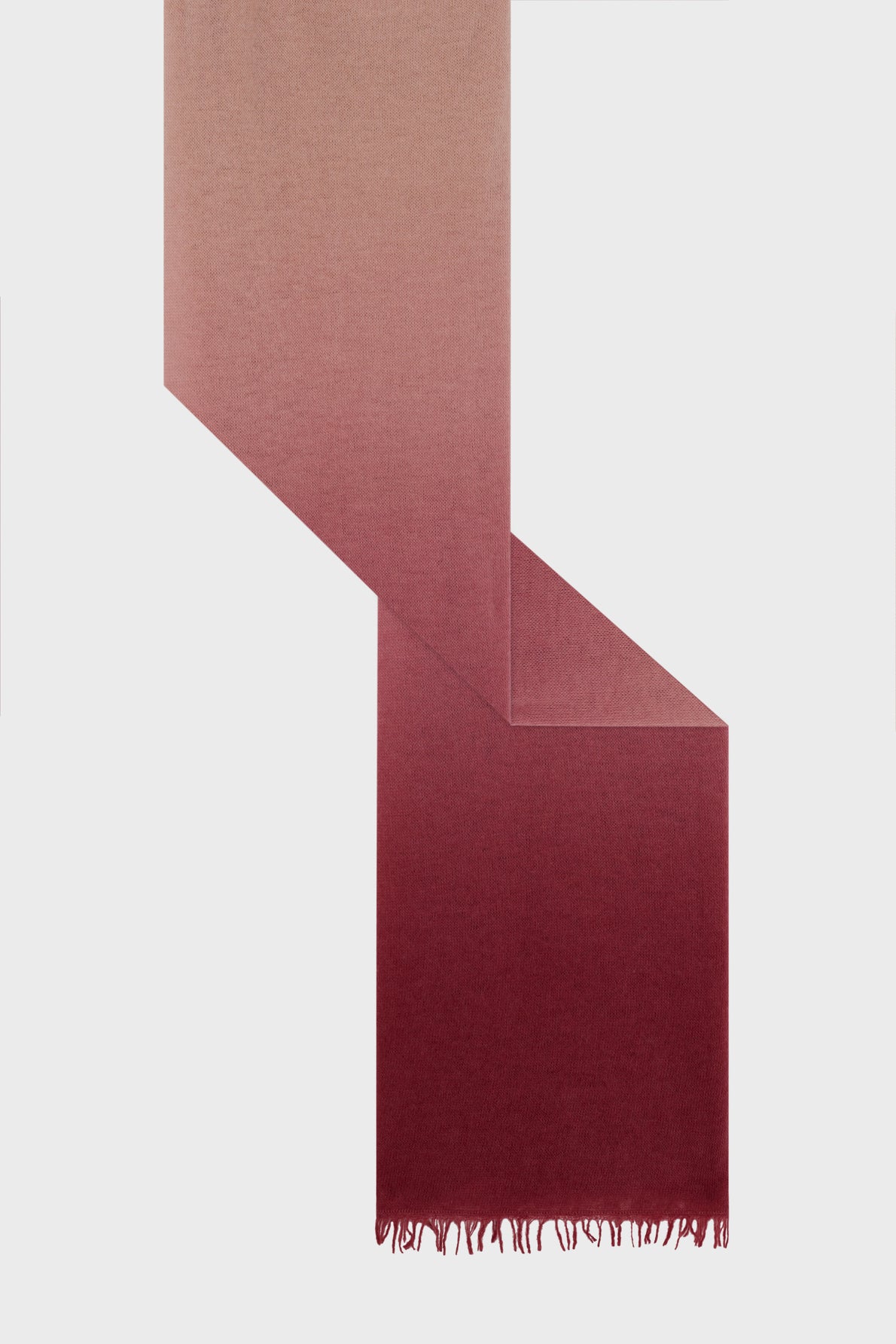 A rectangular echarpe rose with a gradient from light pink at the top to deep burgundy at the bottom, displayed in a zigzag pattern and ending with short fringe. This elegant echarpe laine adds a touch of warmth and sophistication to any outfit.