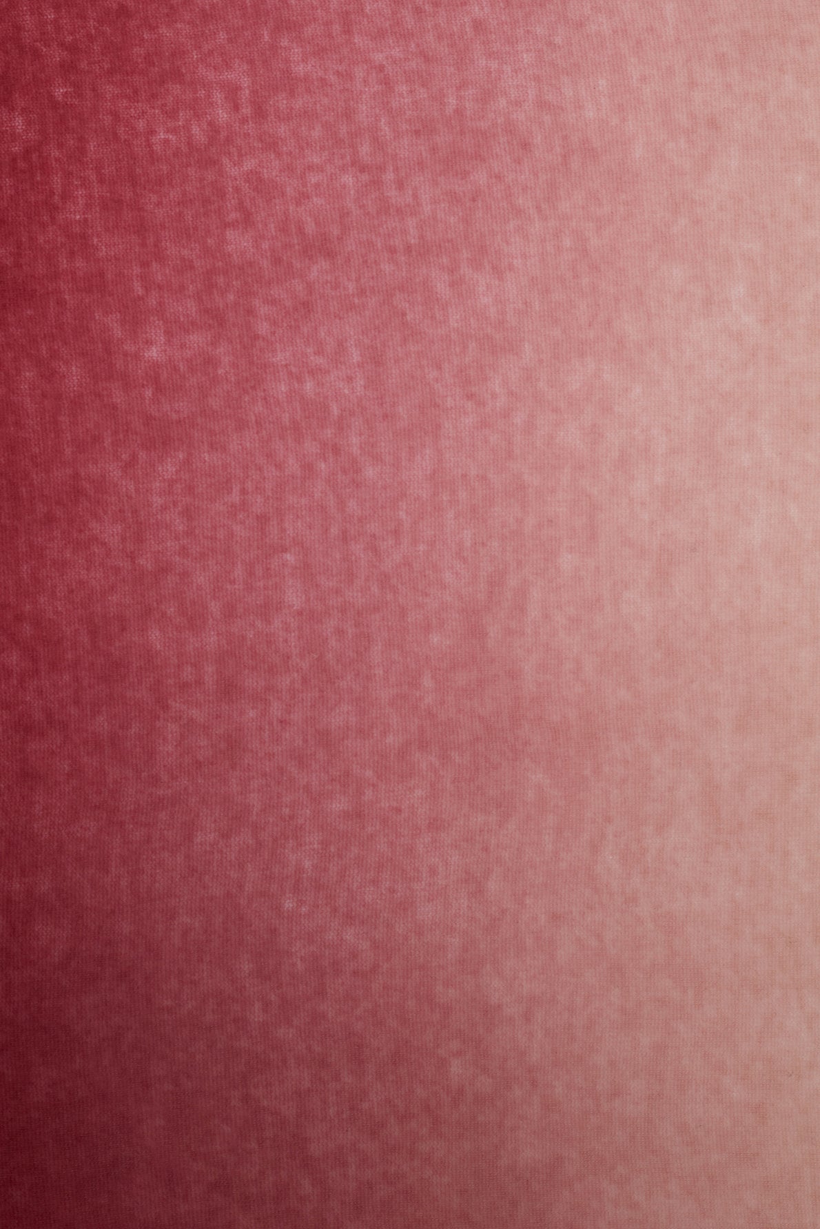 A close-up of a textured fabric surface in shades of reddish-pink, showing a subtle gradient from darker red on the left to lighter pink on the right—evoking the soft elegance of an echarpe cachemire or an exquisite echarpe rose.