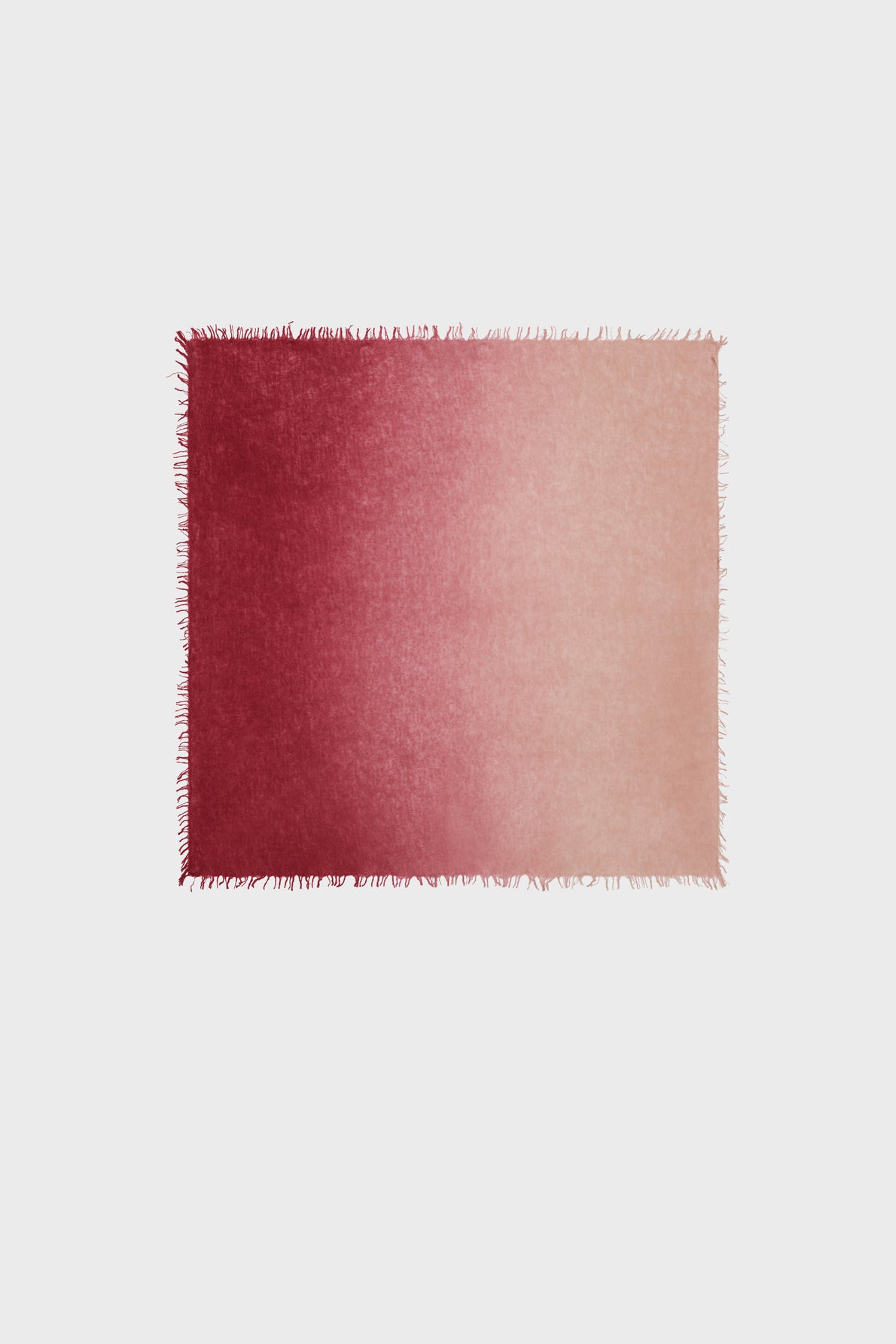 A rectangular rug with fringe edges, reminiscent of an élégante echarpe rose, featuring a gradient color transition from deep red on the left to light pink on the right, set against a plain white background.