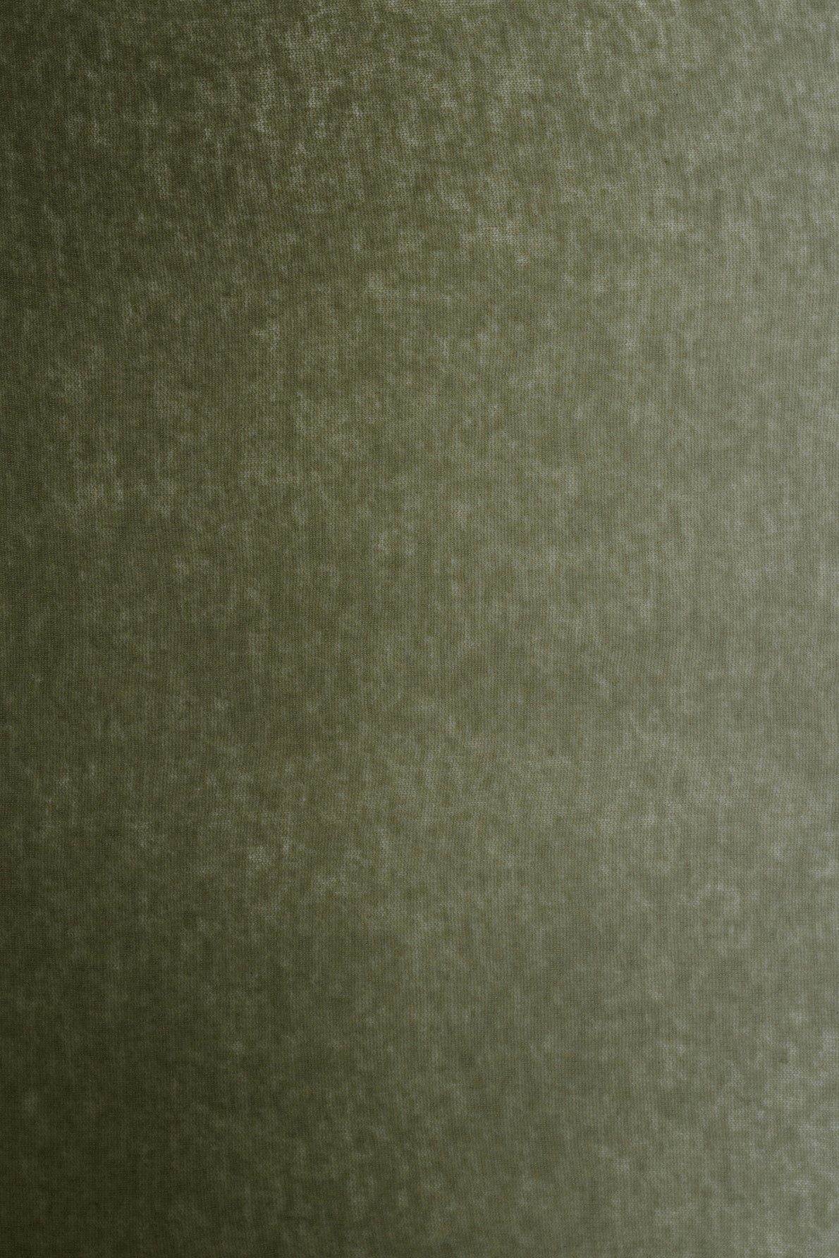 Faded olive green textured surface, possibly fabric or painted wall, with a soft, slightly mottled appearance reminiscent of an écharpe laine or an elegant écharpe kaki.