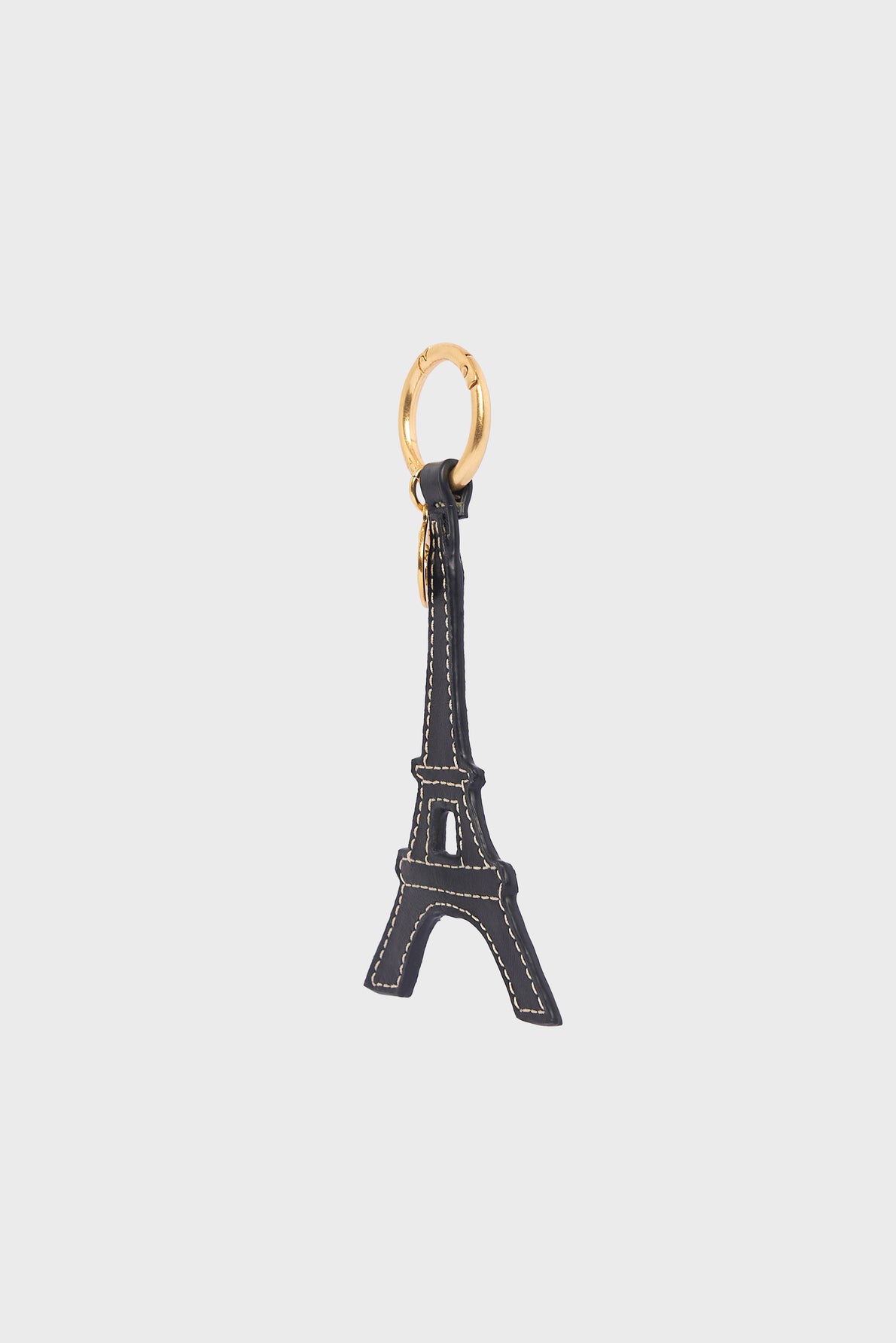 A porte-clé tour Eiffel shaped like the iconic Parisian landmark, crafted from dark cuir de vachette with elegant white stitching, and attached to a gold-colored keyring.