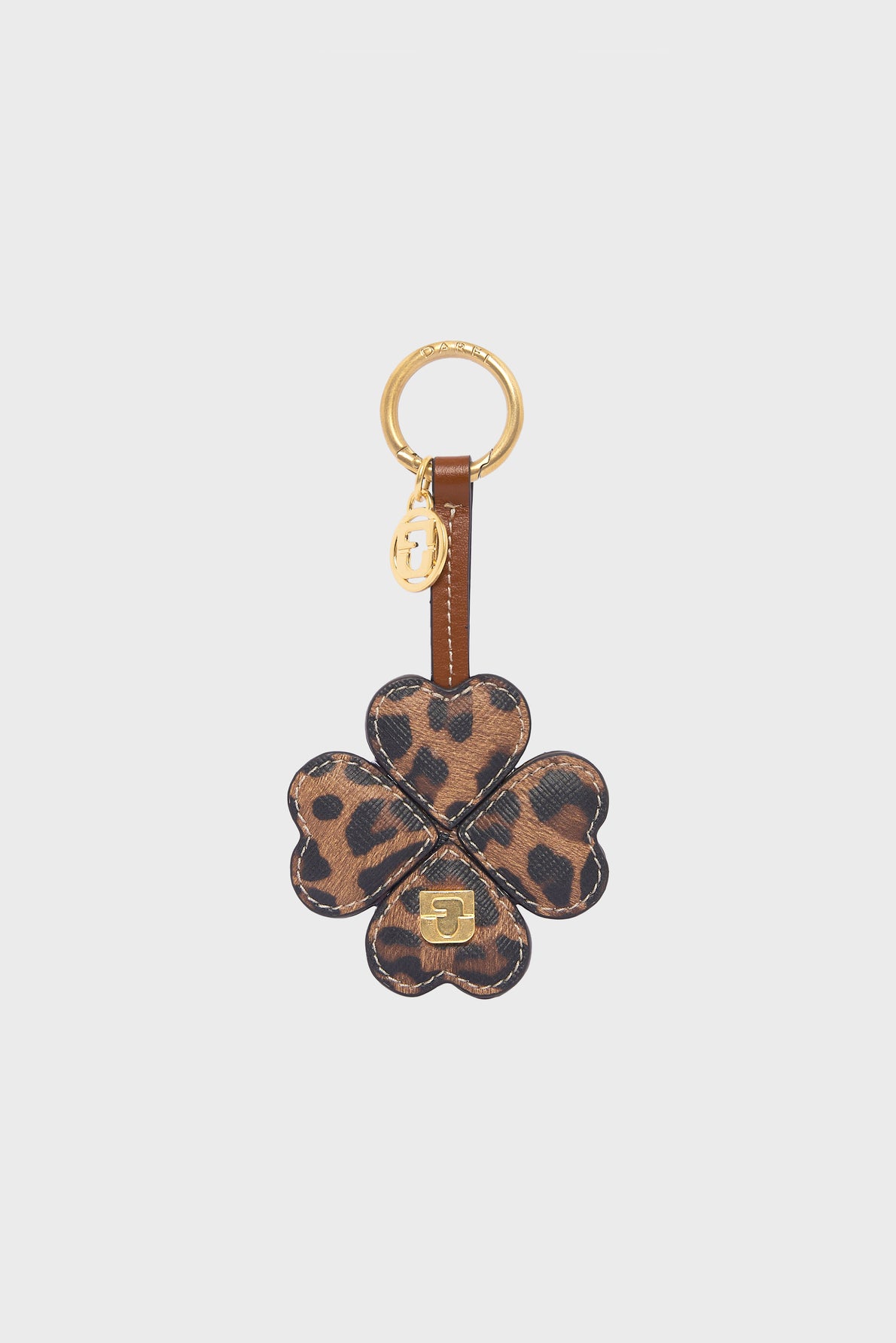 A gold keyring with a charm shaped like a four-leaf clover, crafted from toile enduite léopard and featuring a small gold emblem at the center—perfect as a porte-clé trèfle or an elegant charm de sac.