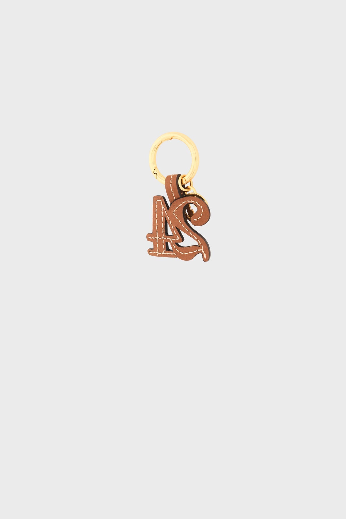 Brown leather porte-clé cuir with white stitching, shaped into the intertwined letters L and S, attached to a gold metal keyring reminiscent of a médaille GD, centered on a plain light gray background.