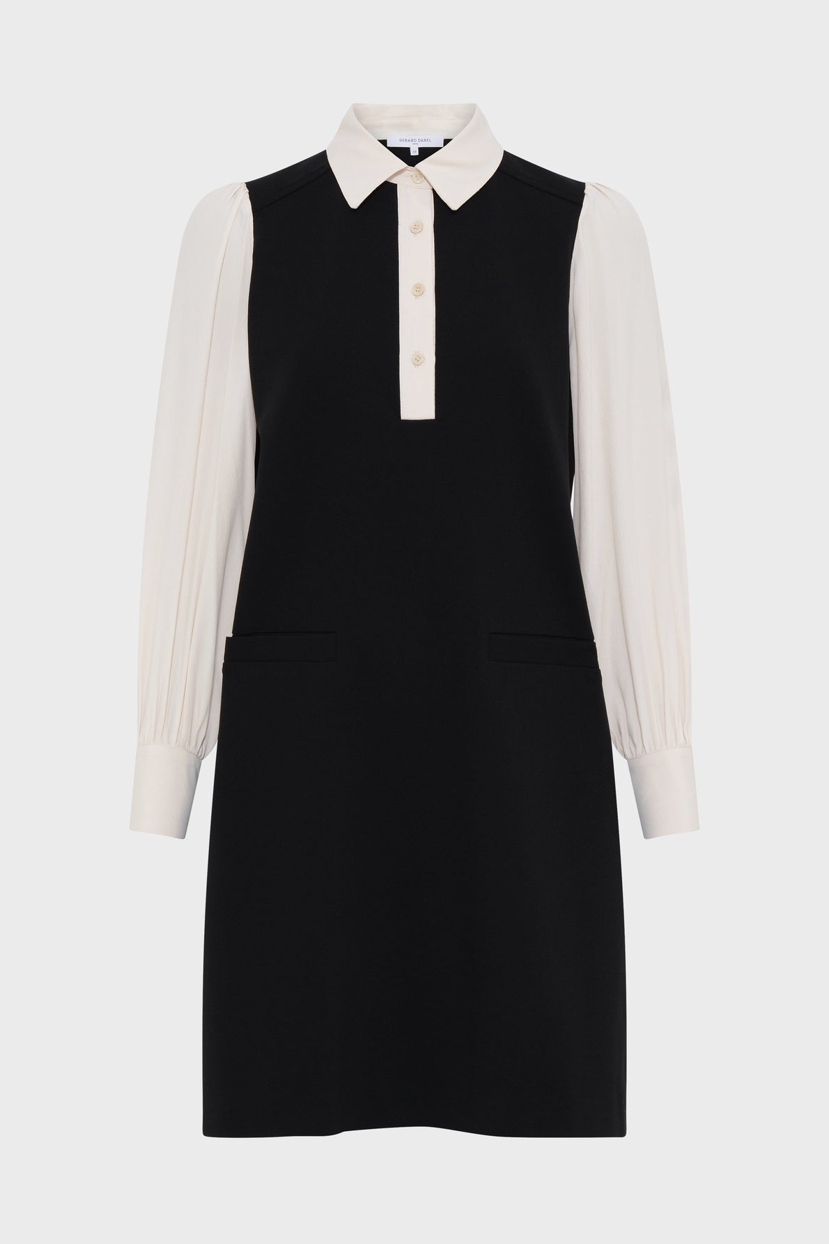 A chic robe bicolore, this black sleeveless dress is paired with a white col chemise underneath, featuring long white puffed sleeves, buttoned cuffs, and a front button placket. The robe courte is styled with two functional front pockets for added flair.