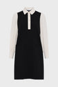 A chic robe bicolore, this black sleeveless dress is paired with a white col chemise underneath, featuring long white puffed sleeves, buttoned cuffs, and a front button placket. The robe courte is styled with two functional front pockets for added flair.