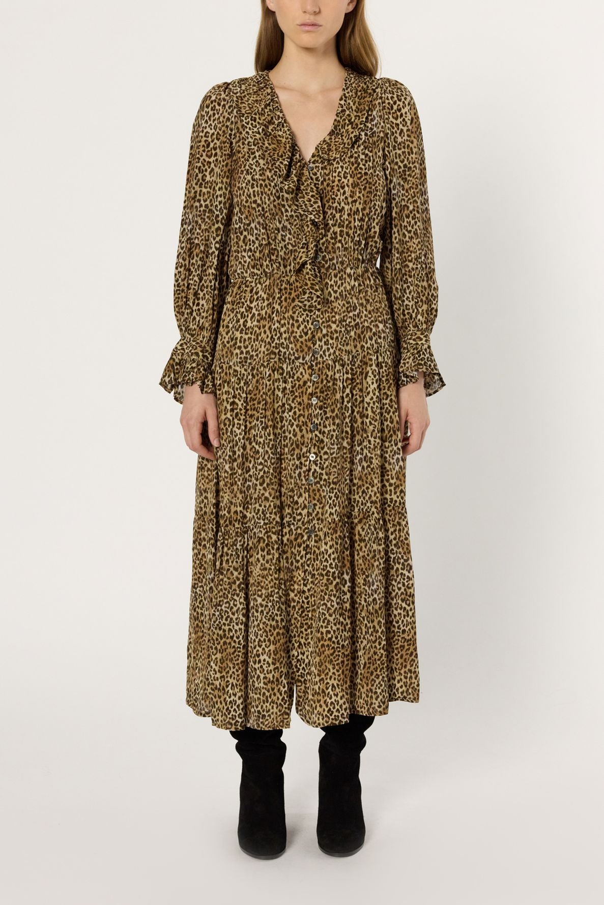 A person wearing a robe longue, léopard print, button-down midi dress with ruffle details, standing against a plain white background, paired with black boots.