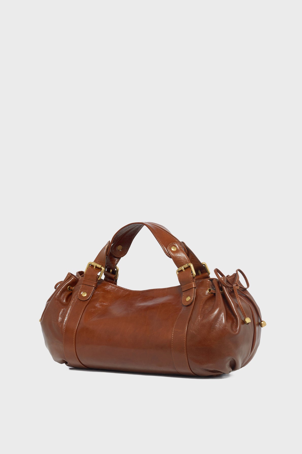 A cylindrical brown cuir froissé leather sac à main with gold hardware, two handles, and gathered side details, set against a plain white background.