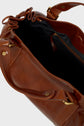 A close-up of an open brown cuir froissé sac à main with gold hardware, showing its black fabric interior and a zippered pocket inside.