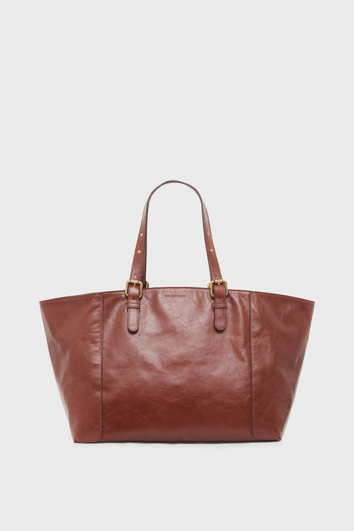 A large brown cabas cuir with two adjustable shoulder straps and gold buckle details, this sac porté épaule is displayed against a plain white background.