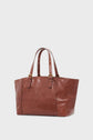 Brown leather tote bag with two handled straps featuring gold buckles and stud accents, set against a plain light background. This cabas cuir boasts a smooth, slightly shiny finish, making it a sac à main chic perfect for any occasion.