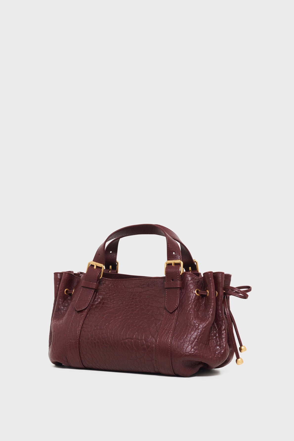A maroon sac à main in cuir bubble leather with gold hardware, textured surface, double handles, and gathered sides, photographed against a plain white background.