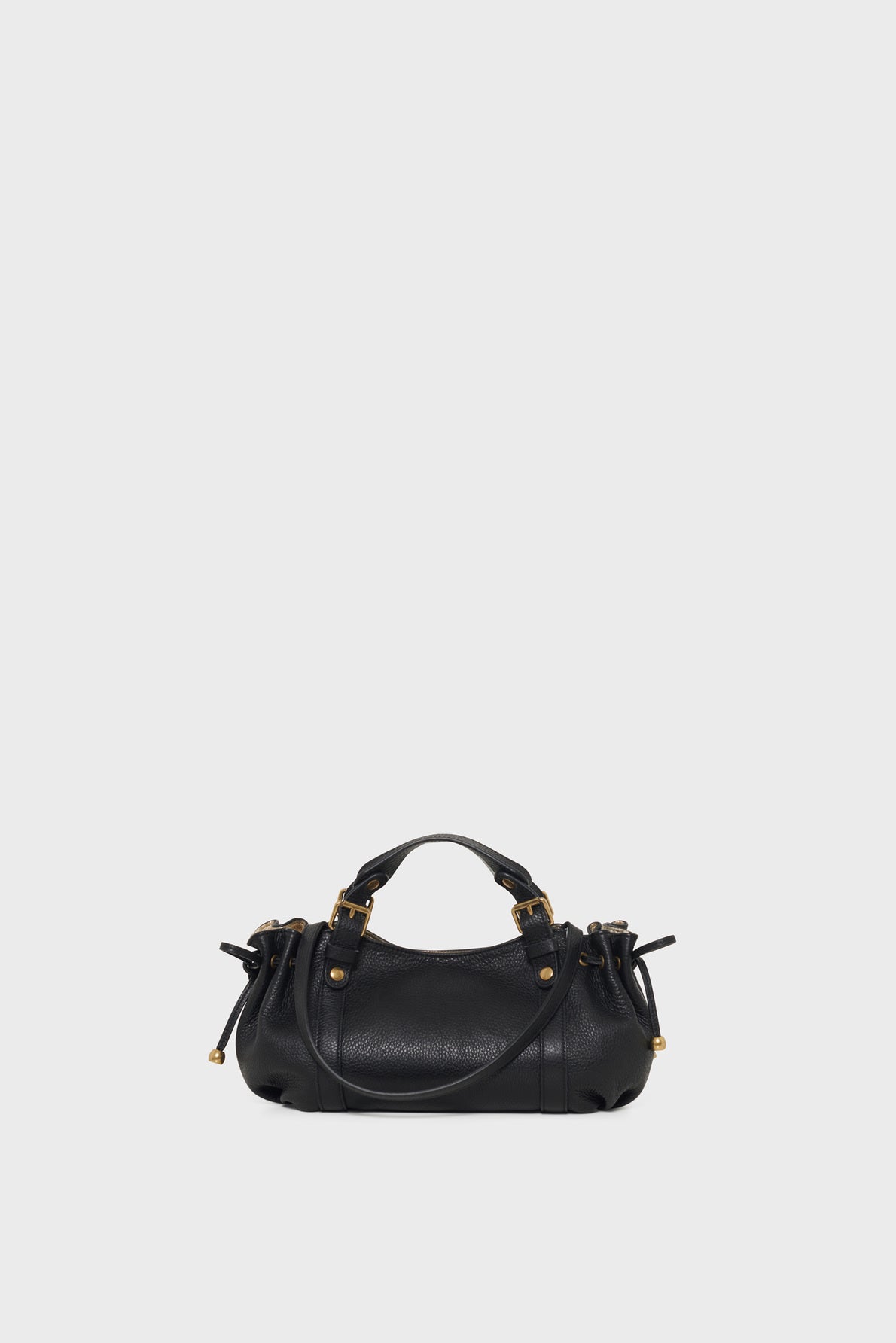 A small black cuir grainé leather mini sac à main with short handles, gold-tone hardware, and decorative side drawstrings, displayed against a plain light gray background.