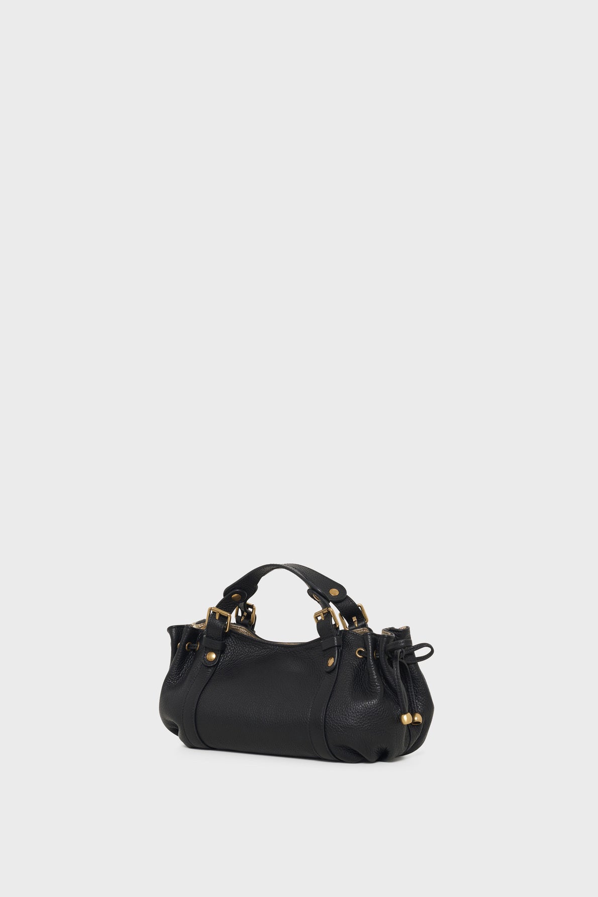 A small black leather handbag with gold hardware, double handles, and a structured, rounded shape crafted from cuir grainé, featuring a bandoulière amovible, set against a plain white background.