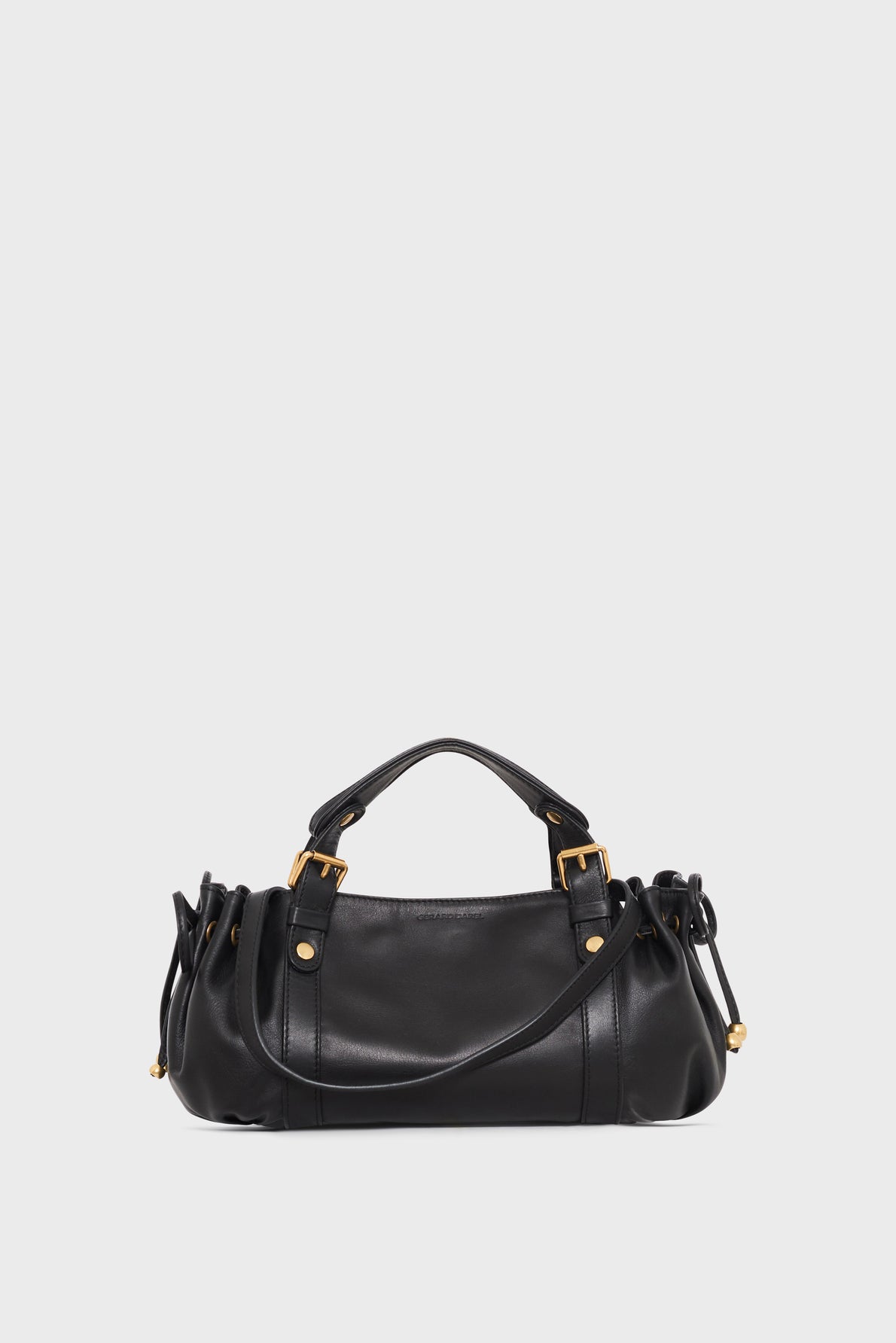 A black leather handbag (sac à main) with gold hardware, double handles, a bandoulière amovible, and side drawstring details, displayed against a plain light gray background.