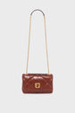 Brown quilted leather sac bandoulière with a gold chain strap and a gold clasp, displayed against a plain white background. This elegant piece showcases the timeless style of a créateur, crafted in luxurious cuir for a sophisticated finishing touch.