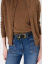 Person wearing a brown sweater and top tucked into high-waisted blue jeans with front pockets and a black belt with a gold buckle. Only the torso and upper legs are visible.