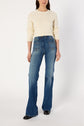 A person wearing a pull écru en laine mélangée with subtle motifs géométriques, high-waisted blue flared jeans, and black shoes stands against a plain white background.