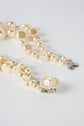 A close-up of a collier double composed of irregular and round pearls, featuring a silver fermoir en métal, displayed on a white background.
