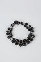 A double-stranded necklace made of round, glossy black beads with a decorative black clasp, displayed on a light gray background.