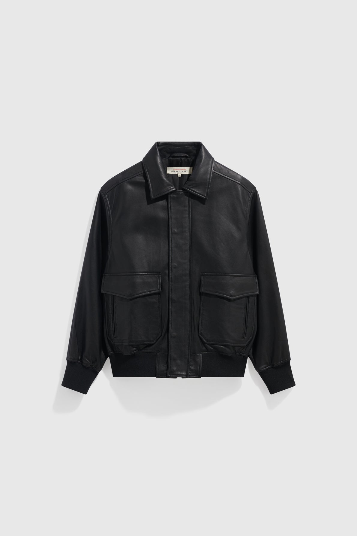 Black leather bomber jacket with a front zipper, two large front flap pockets, a pointed collar, and ribbed cuffs and hem, crafted from luxurious cuir d’agneau and displayed on a plain light gray background.