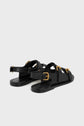 A pair of black sandales plates en cuir with multiple straps and gold buckles is shown on a light grey background, viewed from the back and side angles.