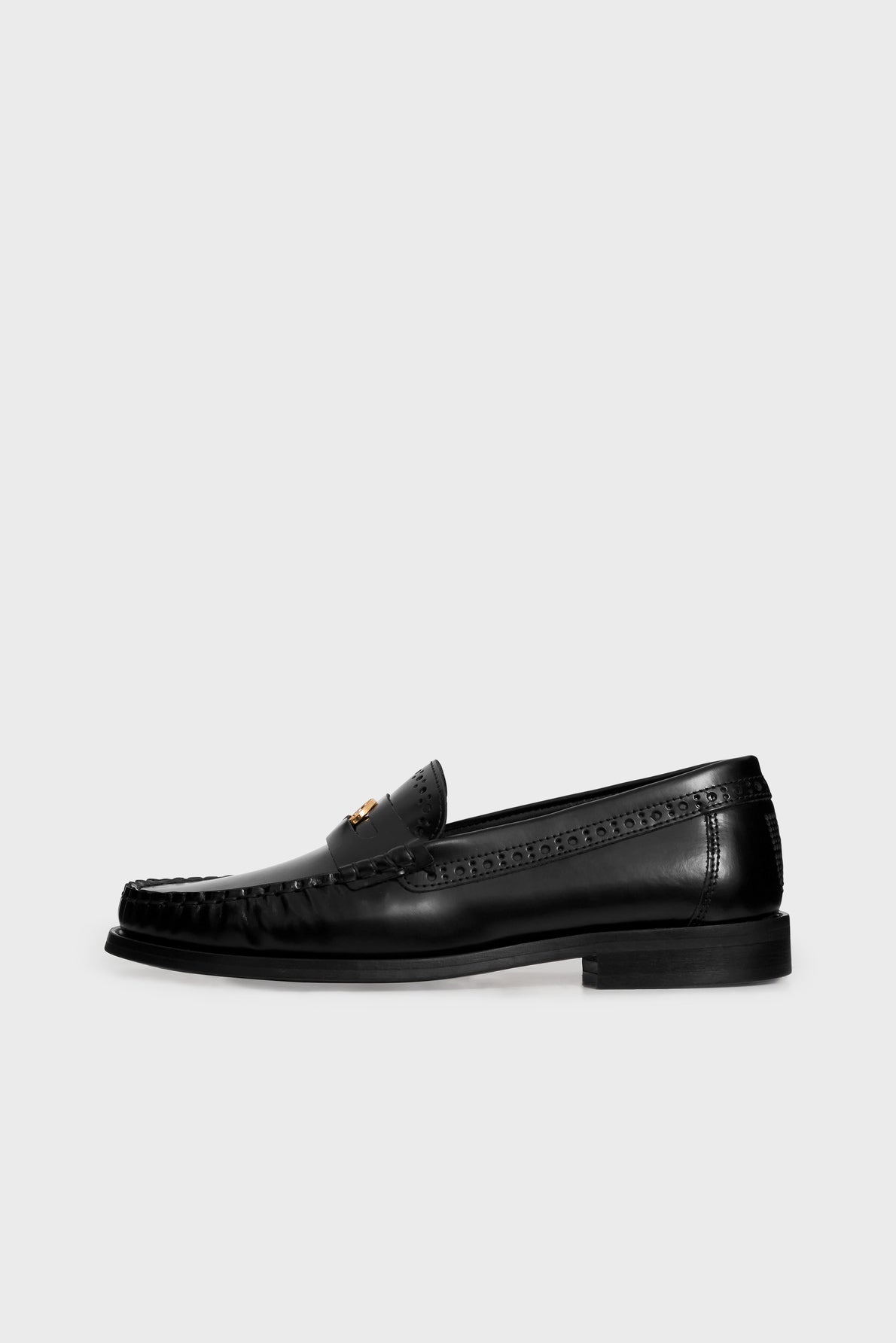 A black leather loafer with decorative stitching, a low heel, and a metal accent on the upper, displayed on a light gray background—these mocassins noirs cuir are the perfect choice for those seeking mocassins femme élégants that blend timeless style with modern sophistication.