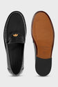A pair of mocassins noirs cuir shown from the top and bottom, featuring a small gold accent on the upper and a brown-and-black sole with Gerard Darel branding and size marking. These mocassins femme élégants are crafted in leather for a refined, timeless look.