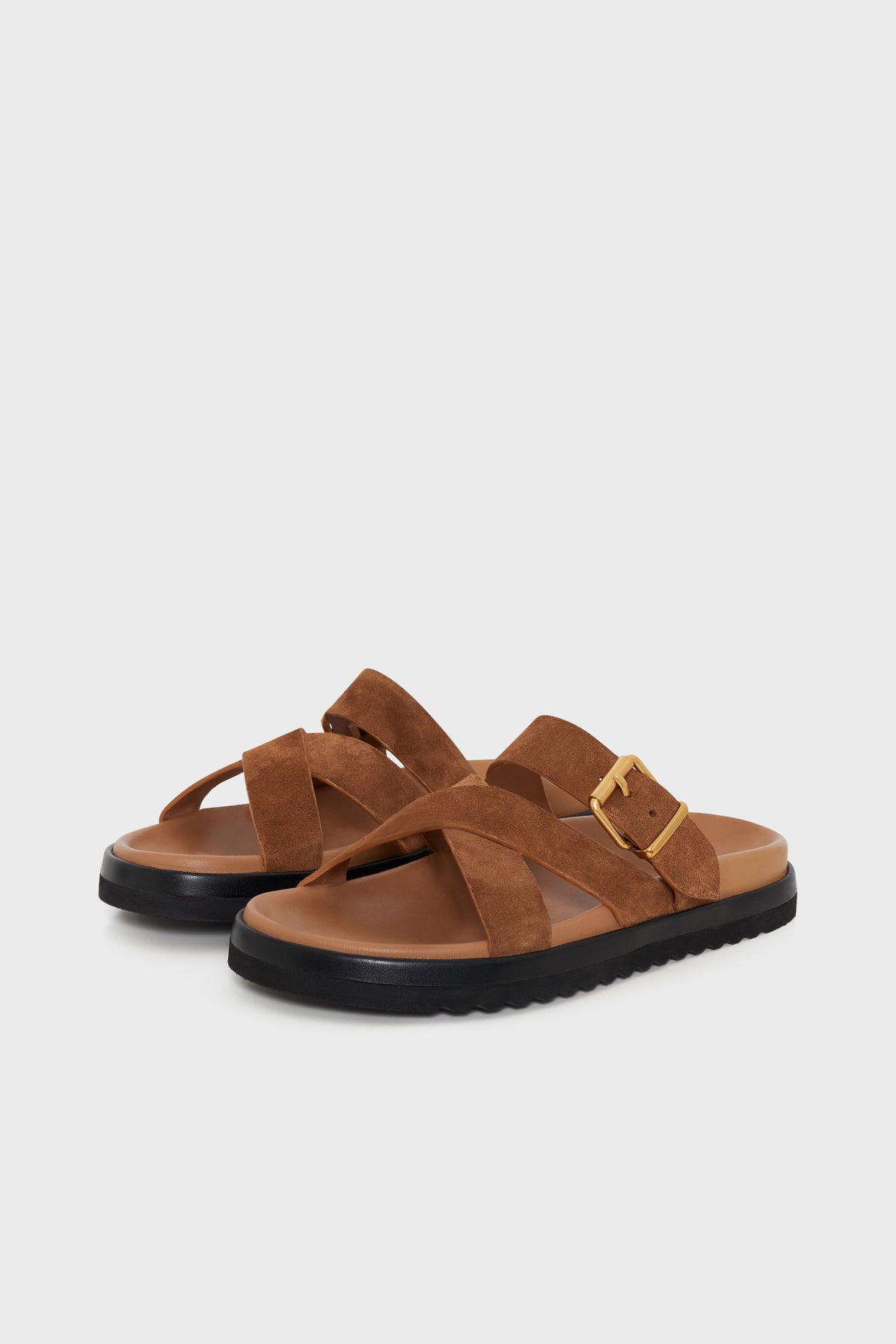 A pair of sandales camel en cuir velours with crisscross straps, a gold buckle detail, and black rubber soles, displayed on a light gray background.