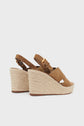 A pair of tan suede wedge sandals with ankle straps and woven natural jute platform heels, shown on a plain white background.