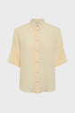 A light yellow, short-sleeved, button-up shirt with a collar, crafted from soft soie and designed in a relaxed chemise oversize silhouette, displayed on a plain white background.