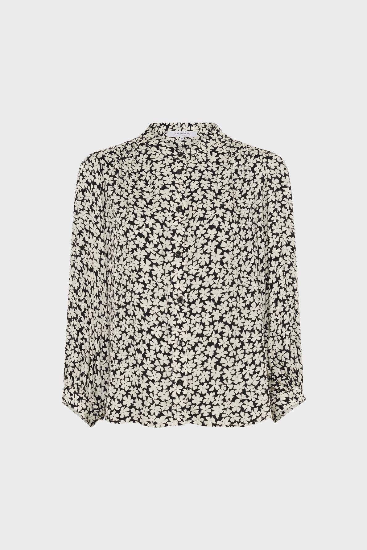 Black long-sleeve blouse with a white floral print. The blouse has a loose fit, a round neckline, and cuffs at the sleeves. The background is plain white.