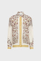 Long-sleeve button-up shirt with a white base, intricate paisley and floral patterns in gold, purple, and brown, and gold trim on the cuffs and hem.