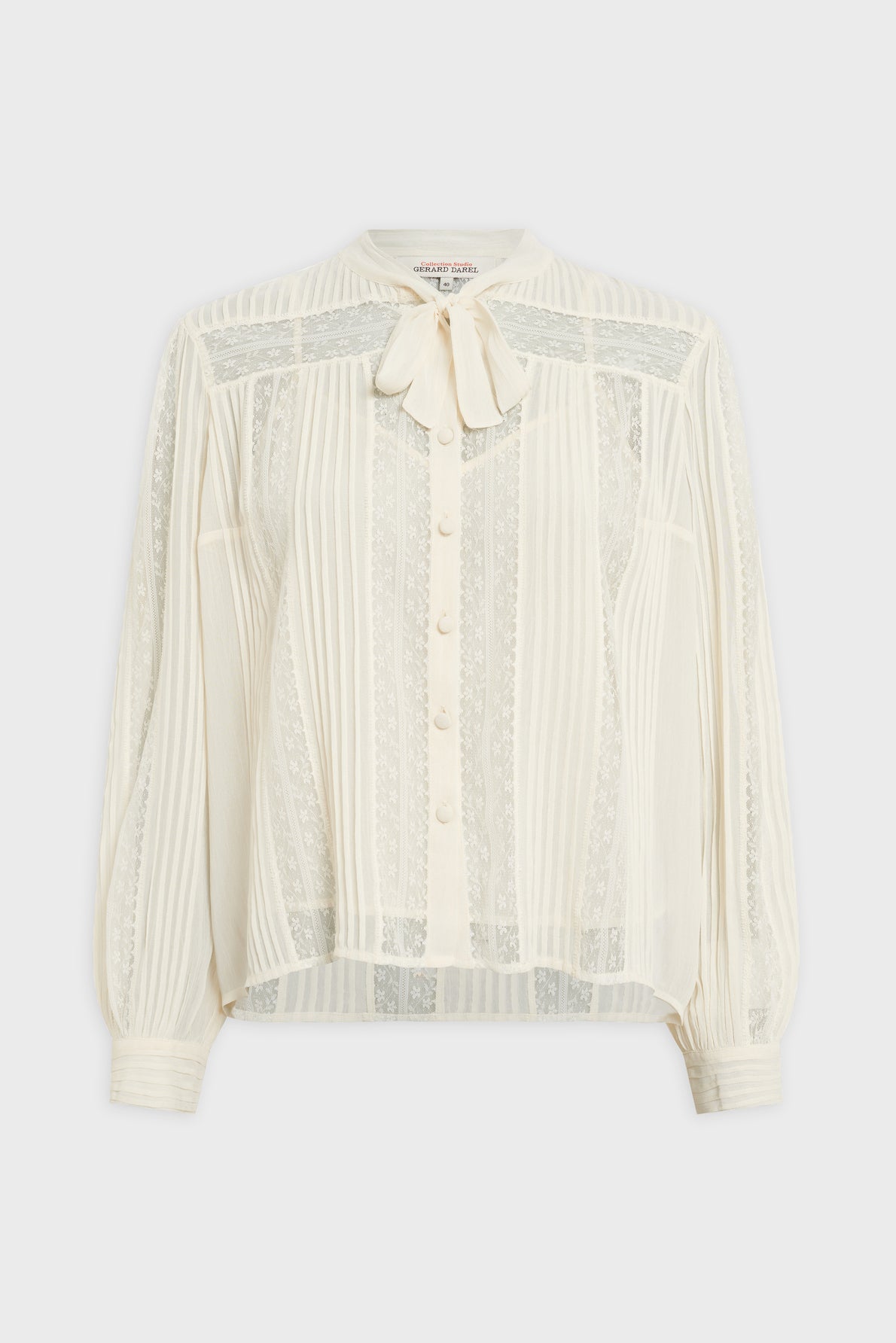Sheer white chemise en dentelle featuring vertical lace panels, a button-down front, long sleeves, and a charming bow tie at the collar.