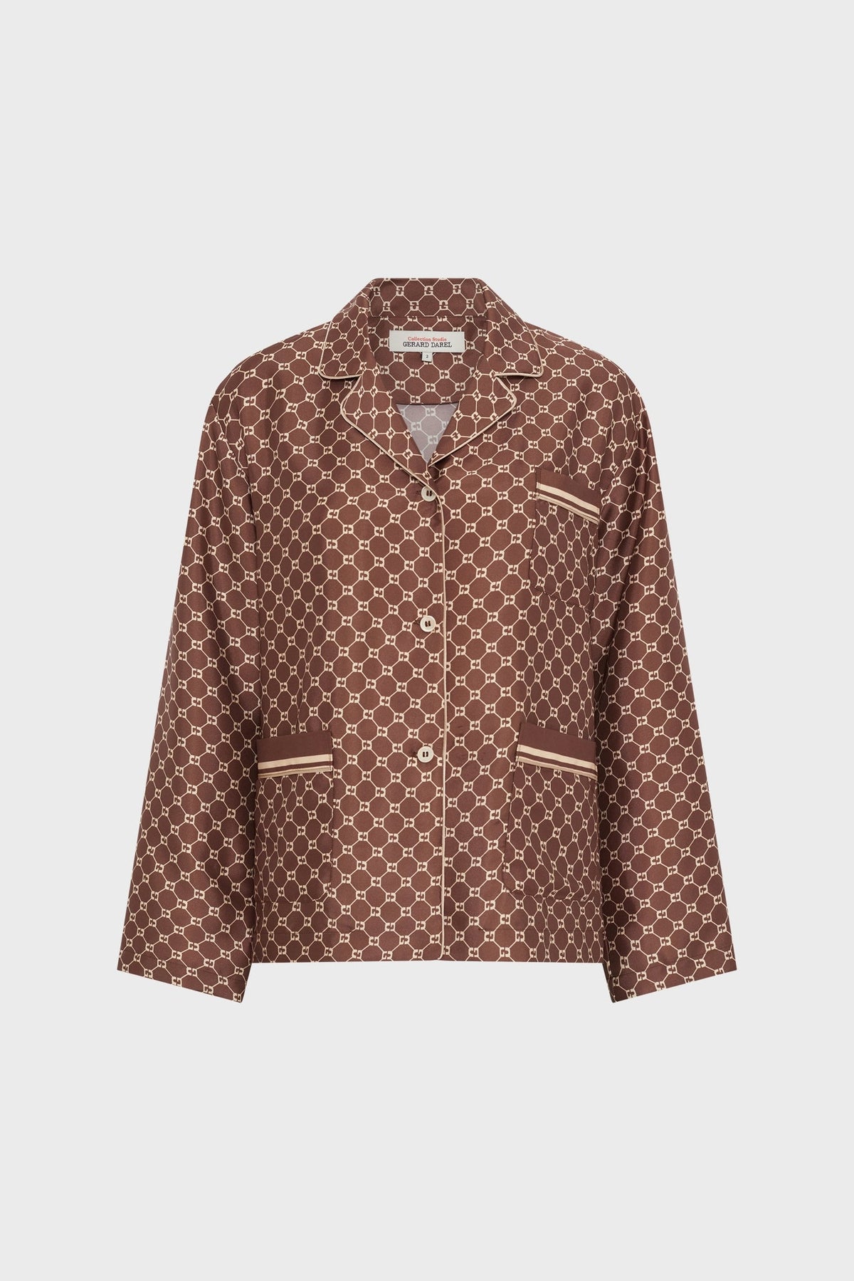 Brown pajama-style chemise satinée with a white geometric pattern and beige trim on the collar, cuffs, pockets, and button placket, featuring a subtle monogramme GD detail, displayed against a plain white background.