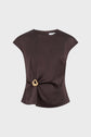 Dark brown, top sans manche satin marron with a round neckline and a bijou doré circular buckle detail on the left waist, creating gentle draping. The background is light gray.
