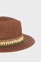 A brown woven hat with a brim, crafted from paille tressée, featuring a decorative ruban tressé in green, tan, and yellow around the crown, displayed against a plain light gray background.
