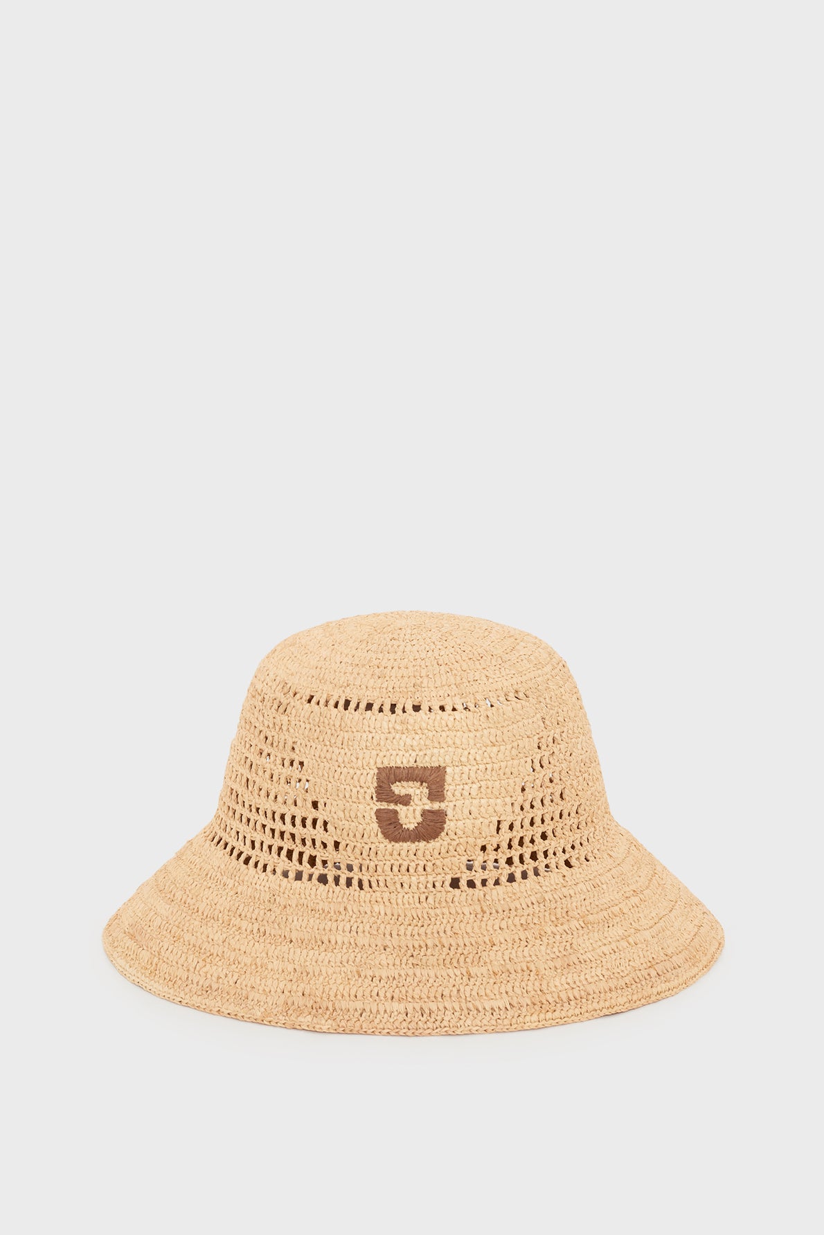 A light brown bob en raphia bucket hat with a wide brim and a dark brown logo on the front, displayed against a plain white background—an effortlessly chic accessoire bohème for sunny days.